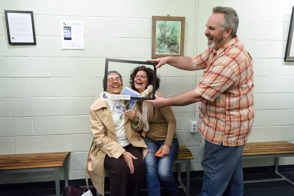 Joe Wall helps Judith Davis and Melissa Ehrenreich learn how to use a frame to take a selfie at the GAC Open House last Friday.